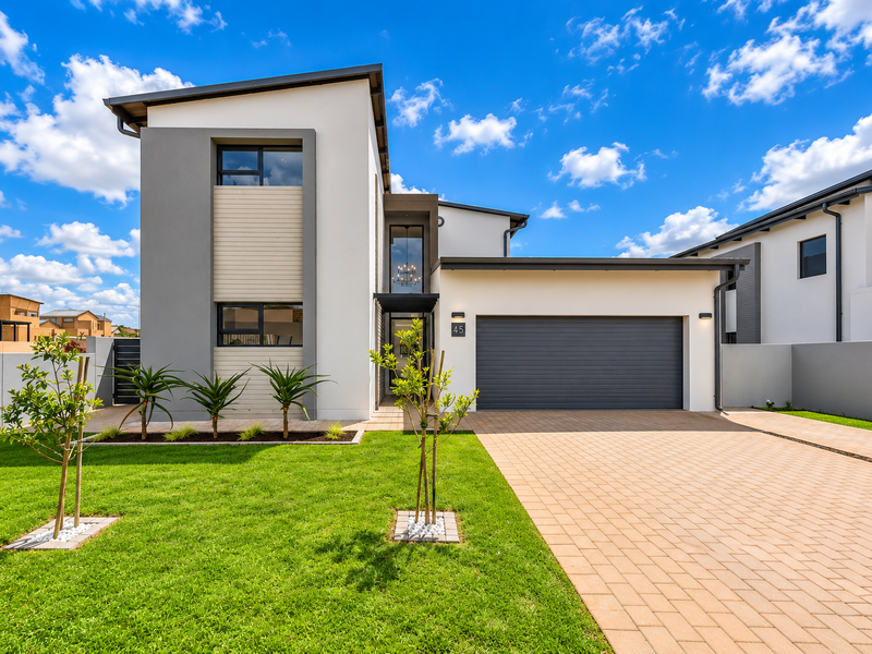 Modern double-story home featuring a clean architectural facade, paved driveway, double garage, and a well-maintained front garden.