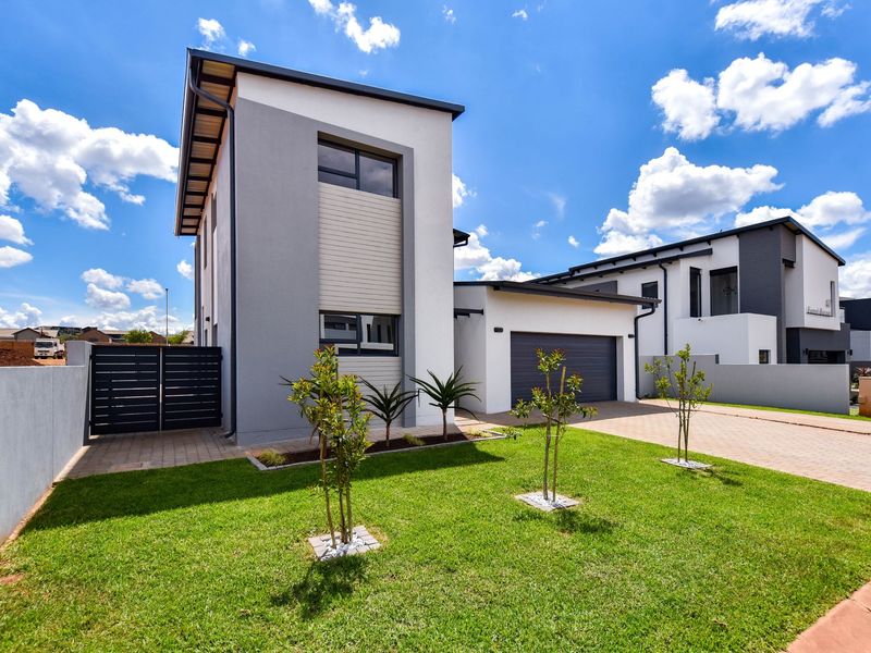 Modern double-story residential home featuring a paved driveway, double garage, and well-maintained front garden with contemporary architectural finishes.