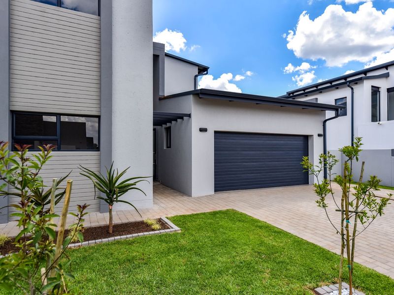 Modern double-storey home exterior featuring a paved driveway, double garage, and well-maintained landscaped garden area.