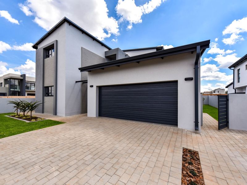 Modern double-storey home exterior featuring a paved driveway, double garage, and neat landscaped garden area.