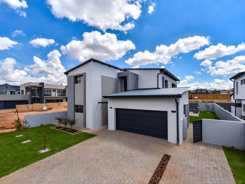 Modern double-story residential home featuring a paved driveway, double garage, and well-maintained garden within a secure estate setting.
