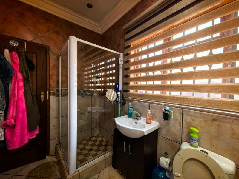 A functional bathroom featuring a shower enclosure, vanity basin, and toilet, finished with tiled walls and flooring.