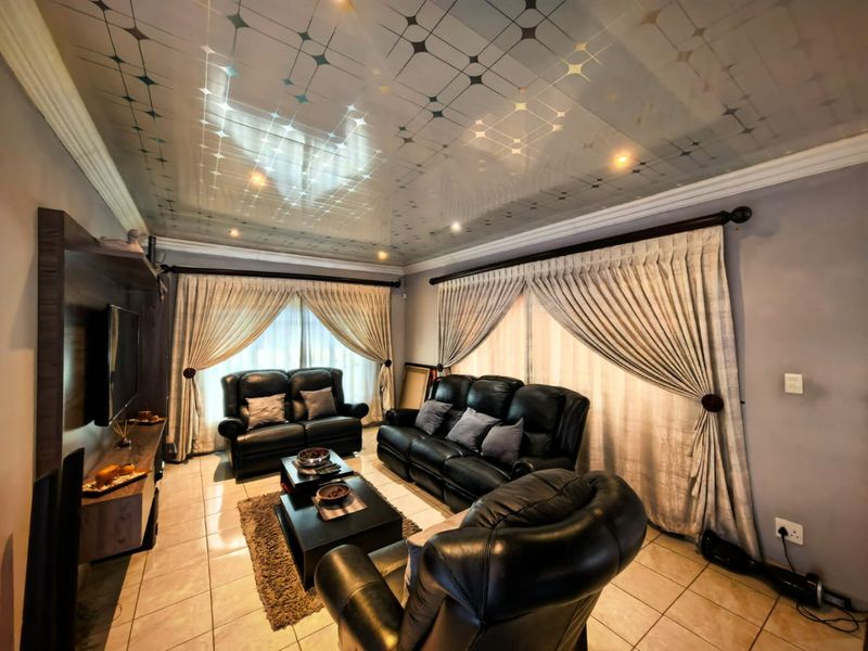 A living room featuring tiled flooring, a decorative ceiling finish, and a built-in media unit, providing a functional space for relaxation.
