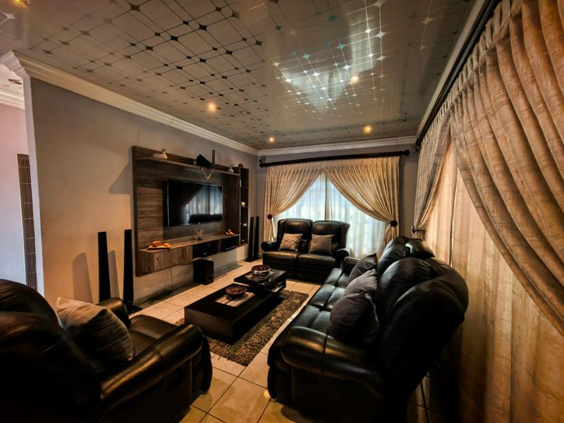A living room featuring a built-in media unit, tiled flooring, and decorative ceiling panels with integrated lighting.