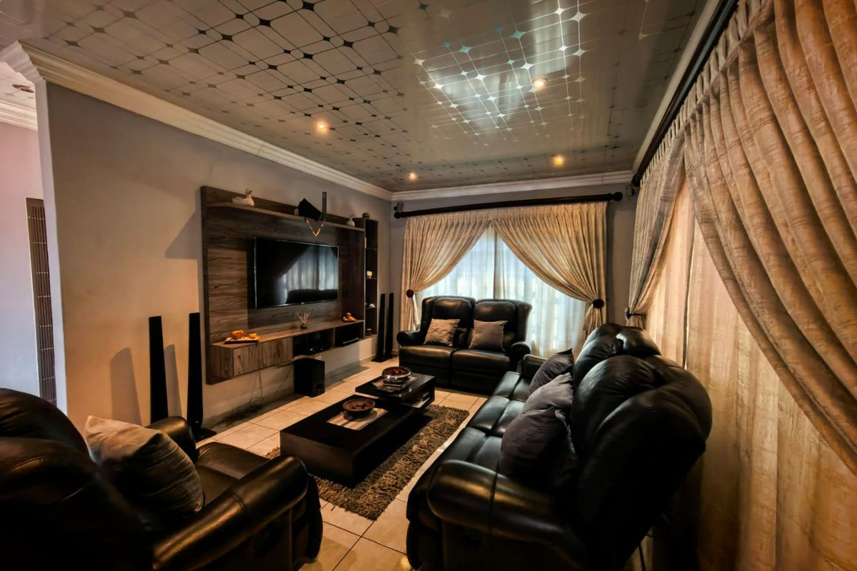 A living room featuring a built-in media unit, tiled flooring, and decorative ceiling panels with integrated lighting.
