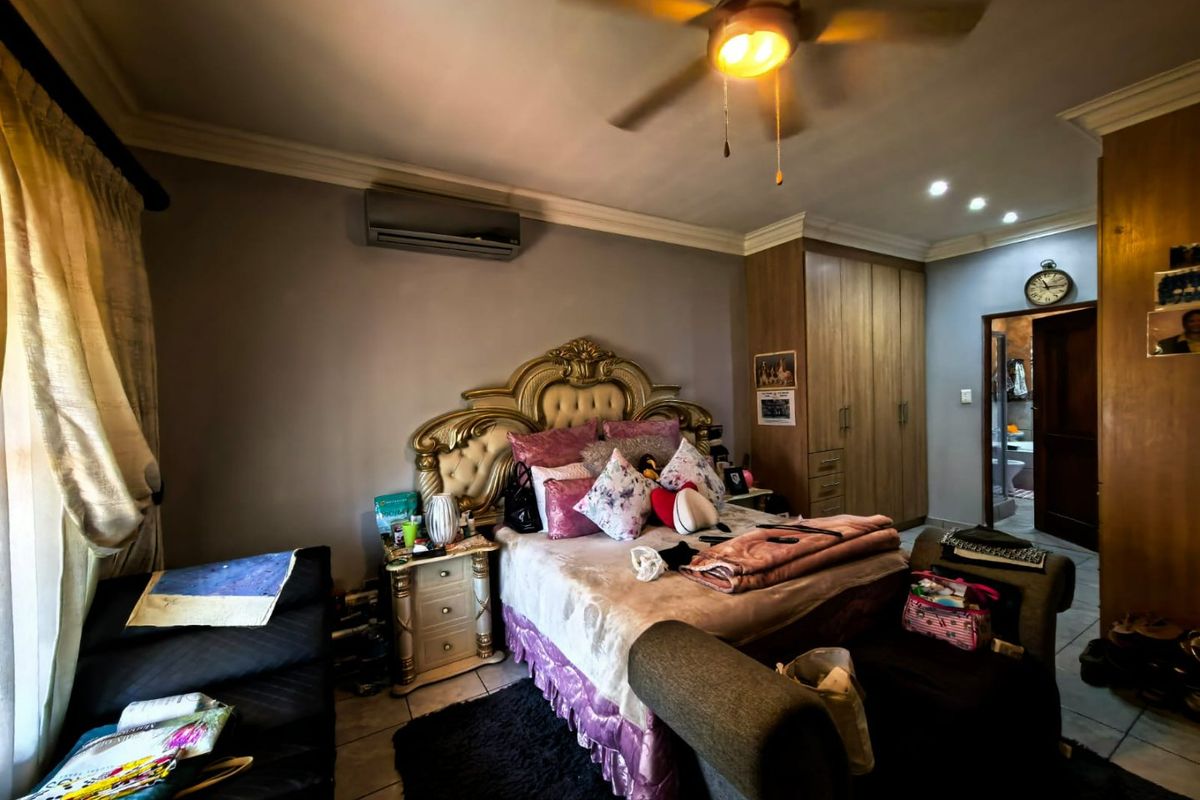 Spacious bedroom featuring built-in cupboards, ceiling fan, and air conditioning unit, with direct access to an en-suite bathroom.