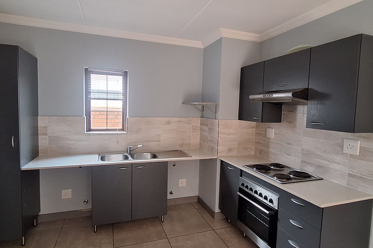 Modern kitchen featuring dark grey cabinetry, light wood-look tiled backsplash, built-in oven, electric hob, and a double basin sink.