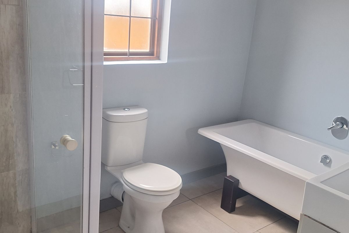 A clean, modern bathroom featuring a freestanding bathtub, a separate glass-enclosed shower, and neutral floor tiling.