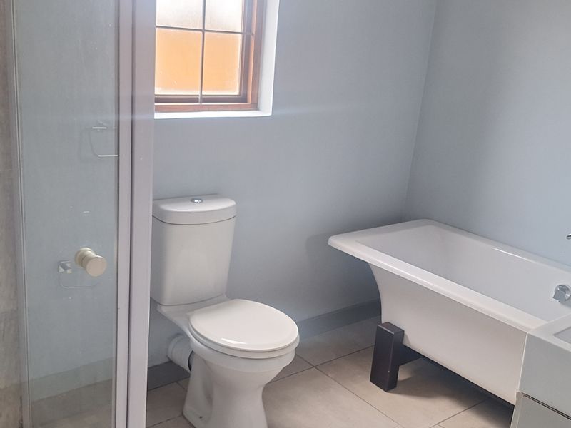 A clean, modern bathroom featuring a freestanding bathtub, a separate glass-enclosed shower, and neutral floor tiling.