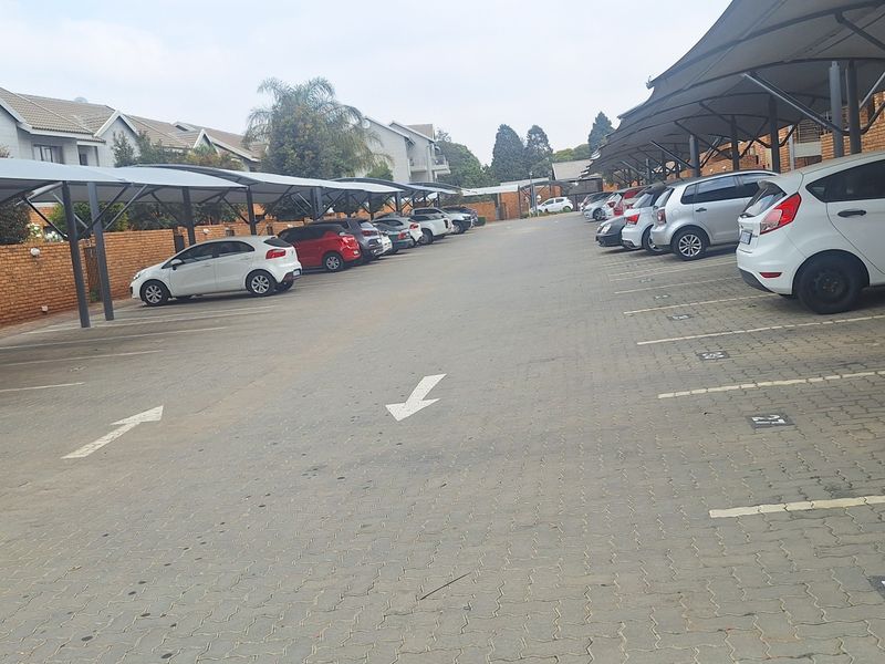 An outdoor parking area featuring covered carports and designated paved parking bays within an apartment complex.
