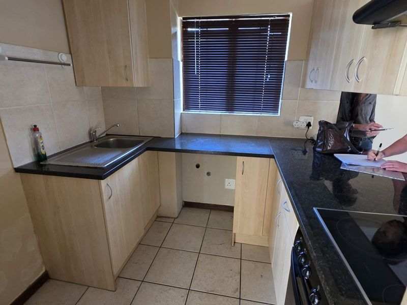 A functional kitchen featuring laminate cabinetry, granite countertops, a stainless steel sink, and an integrated electric hob with an extractor fan.