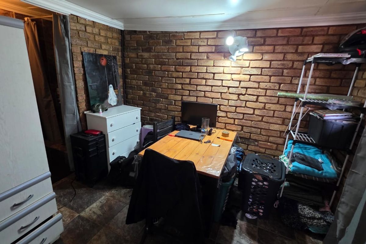 A bedroom featuring an exposed brick feature wall and tiled flooring, offering a rustic aesthetic with potential for modern updates.