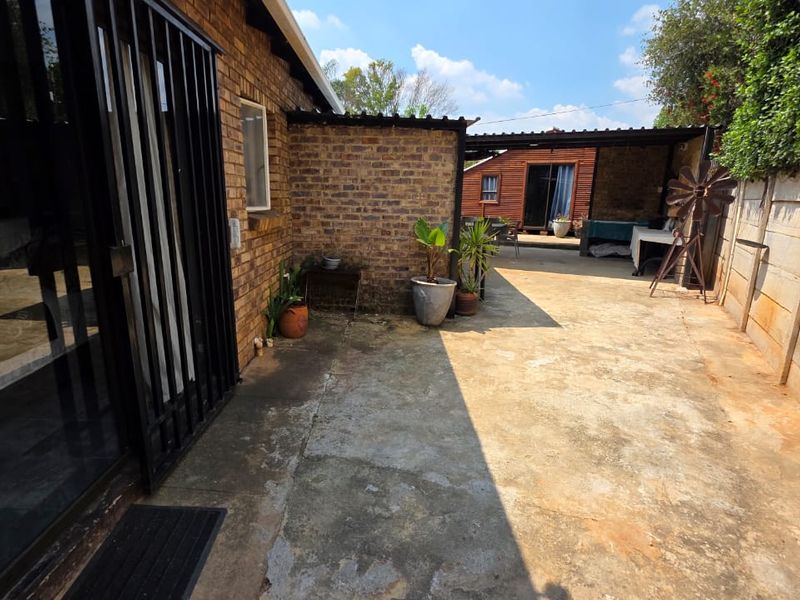 A rear exterior area featuring a brick facade, concrete patio, and a covered outdoor space, offering potential for landscaping or patio improvement.