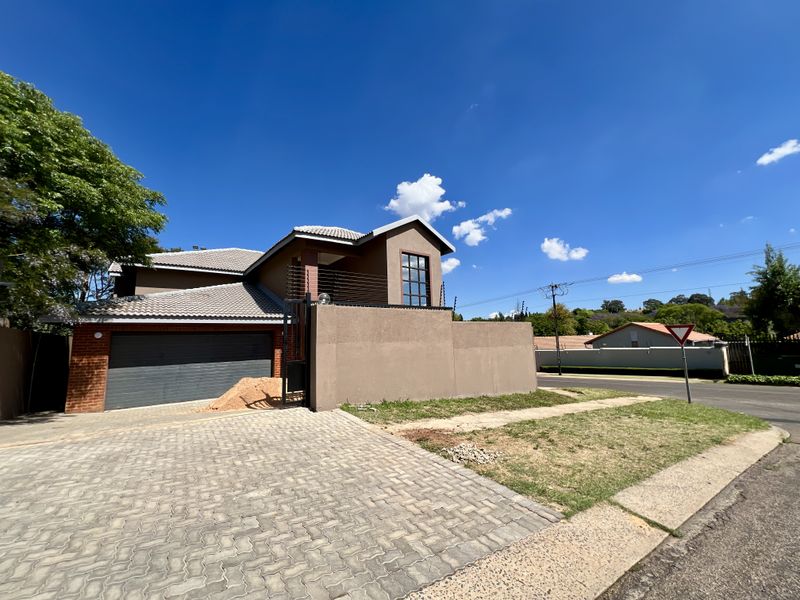 Front exterior view of a double-story house featuring a paved driveway, double garage, and perimeter wall with electric fencing.