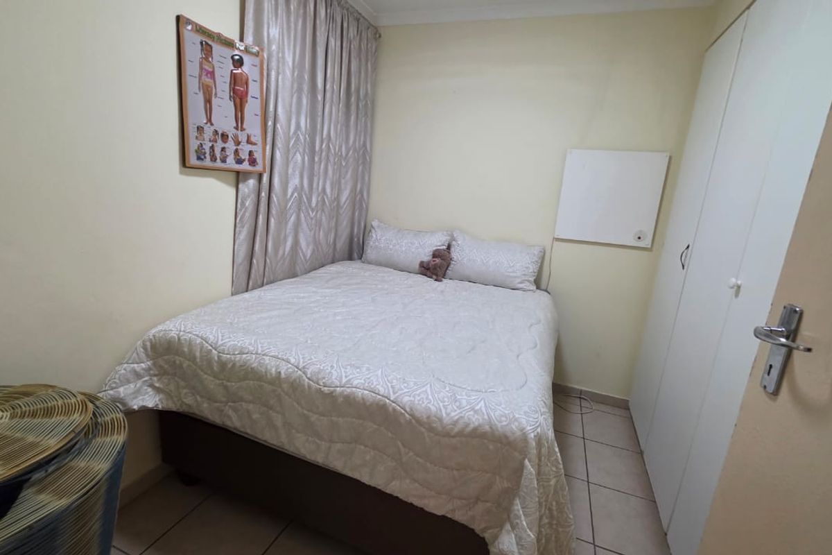 A compact bedroom featuring tiled flooring and a built-in wardrobe, providing functional storage space.