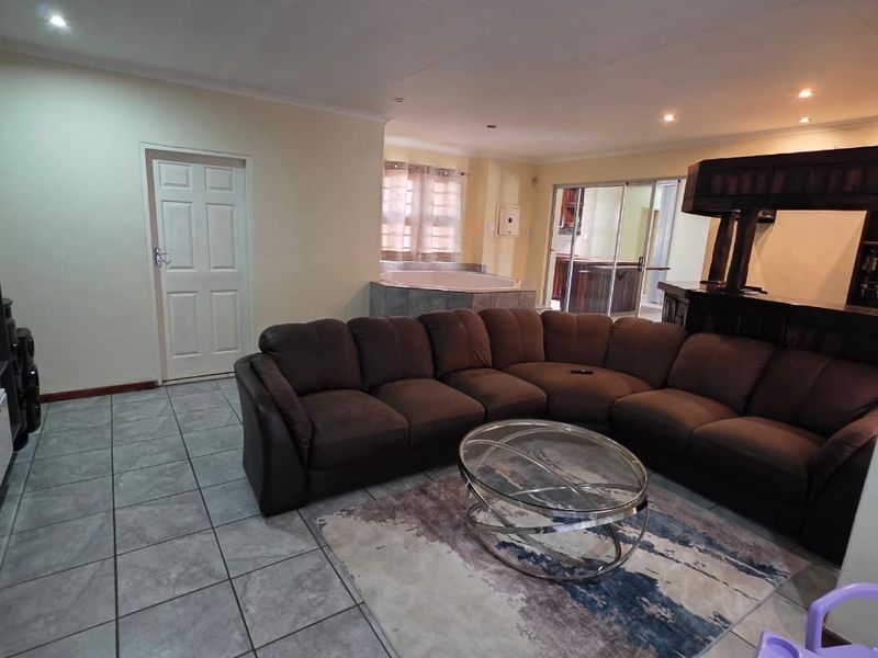 Spacious open-plan living area featuring tiled flooring, recessed lighting, a built-in bar, and a unique integrated corner bathtub.