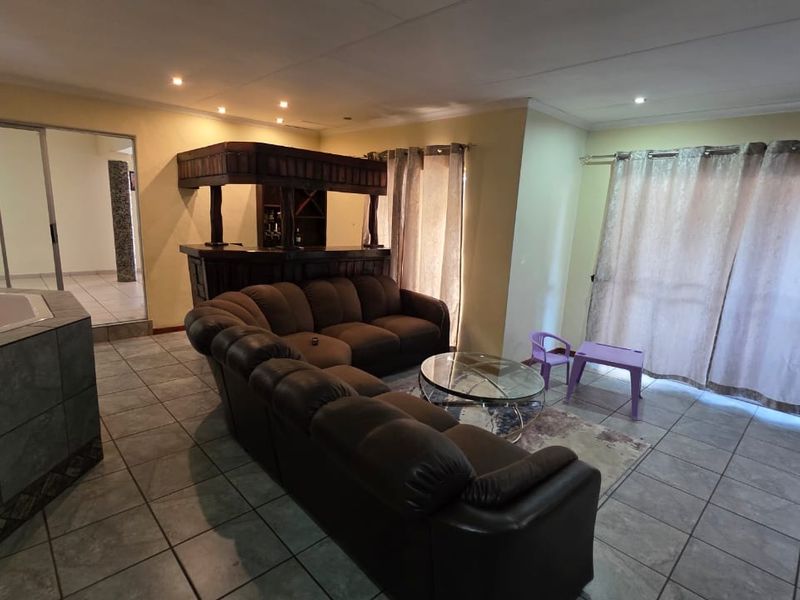 Open plan living area featuring a built-in bar, tiled flooring, recessed lighting, and an integrated corner bathtub, with access to outdoor space via sliding doors.