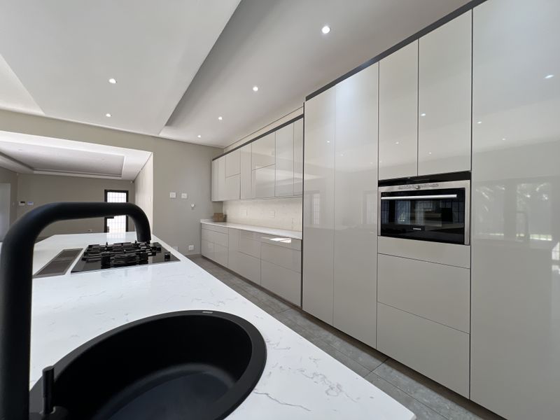 Modern kitchen featuring a large island with quartz countertops, integrated cabinetry, built-in oven, and gas hob, finished with sleek, contemporary fixtures.