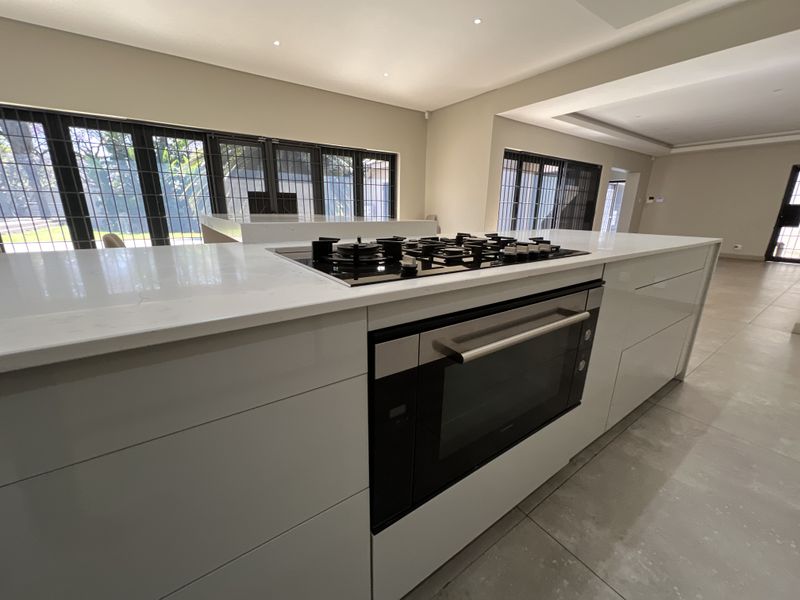 Modern kitchen featuring a large island with a built-in gas hob and oven, stone countertops, and sleek cabinetry in an open-plan layout.