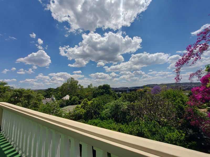 A scenic elevated view overlooking lush greenery and the surrounding neighbourhood, captured from a balcony with a white balustrade.