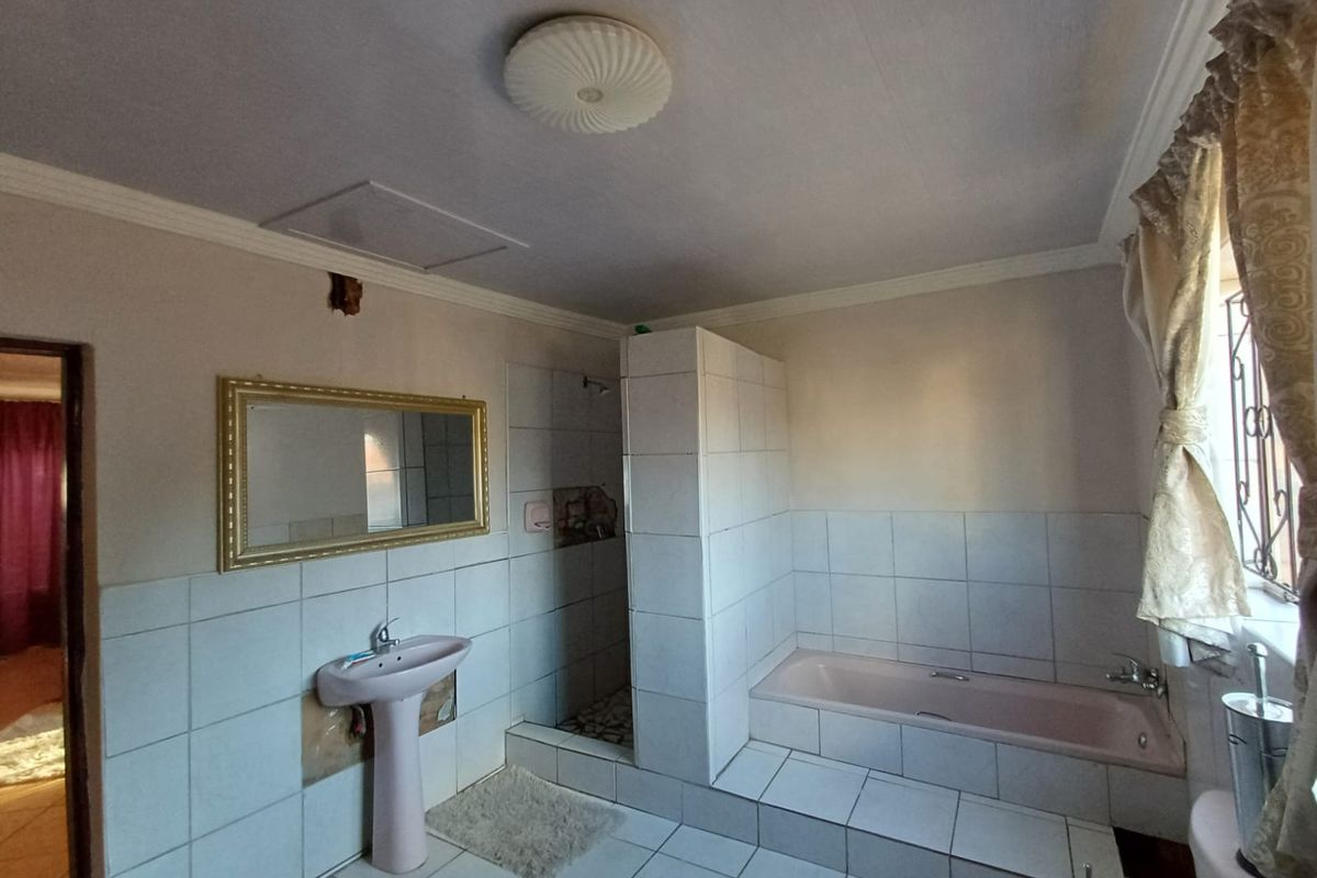 A dated bathroom featuring a pedestal basin, built-in bathtub, and a walk-in shower with tiled finishes throughout.