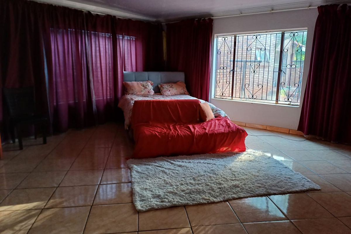Spacious bedroom featuring tiled flooring, large windows with security bars, and a coved ceiling, offering a functional layout with ample natural light.