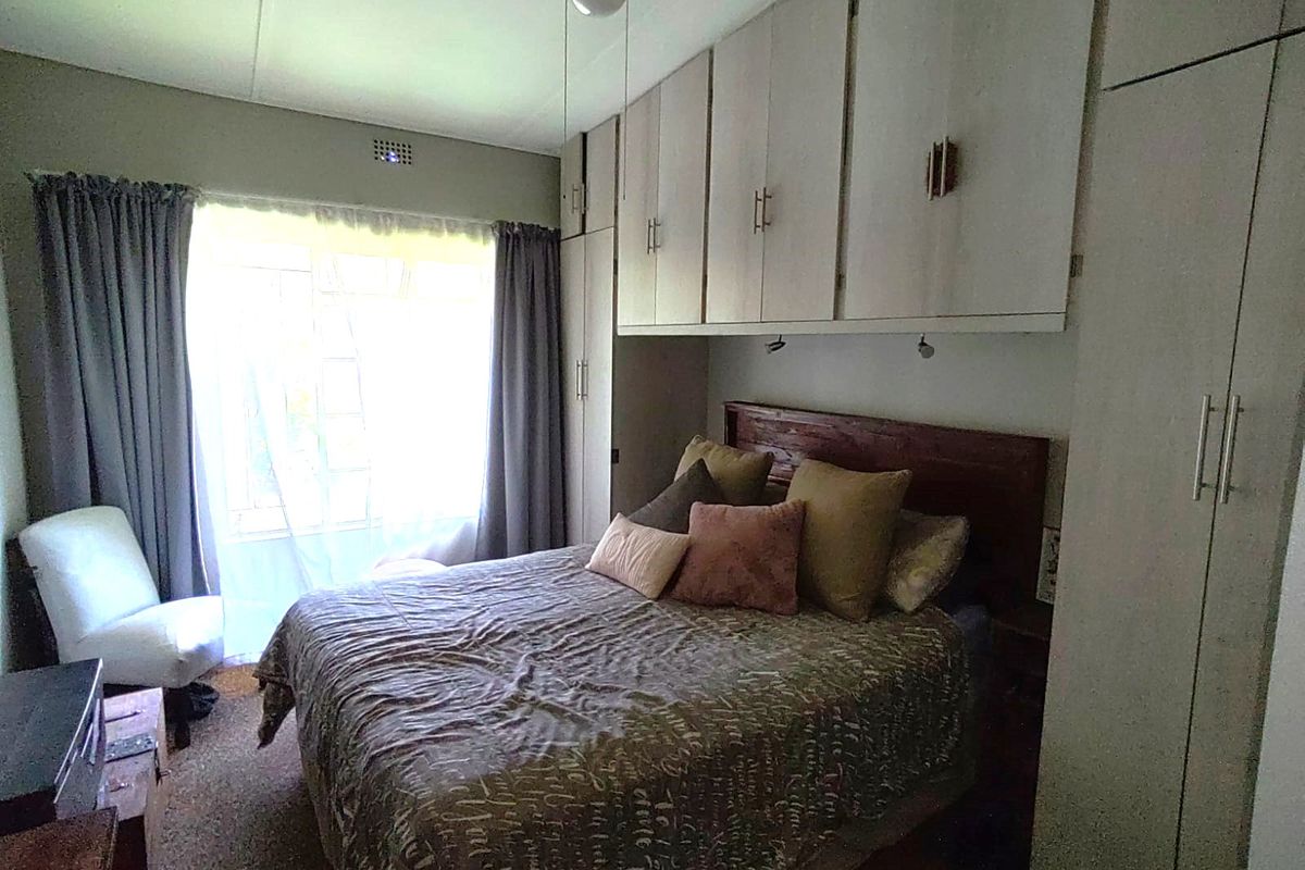 A bedroom featuring extensive built-in cabinetry, a ceiling fan, and natural light from a large window.