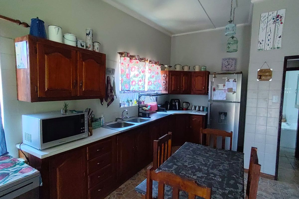 A functional kitchen featuring traditional wooden cabinetry, laminate countertops, a double bowl sink, and tiled flooring, offering a classic and practical layout.