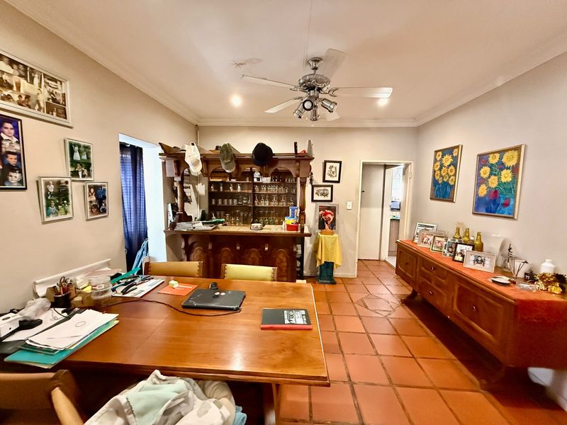 Dining room featuring terracotta floor tiles, a built-in bar, and a ceiling fan, offering a traditional layout with potential for modernization.