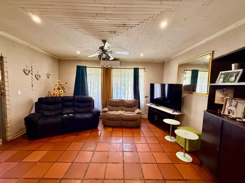 Living room featuring terracotta floor tiles, a timber plank ceiling with a ceiling fan, and a wall-mounted split-system air conditioner.