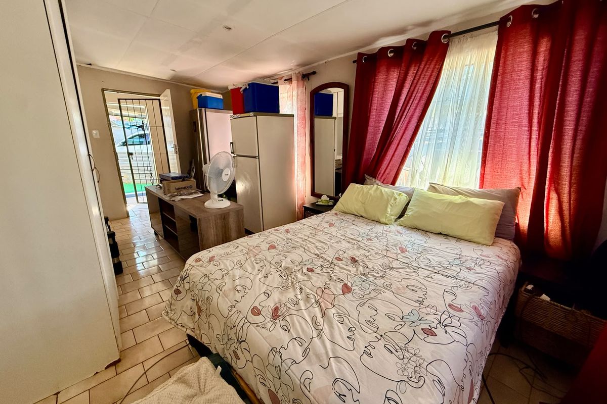 A bedroom featuring tiled flooring, a built-in cupboard, and direct access to an exterior security gate.