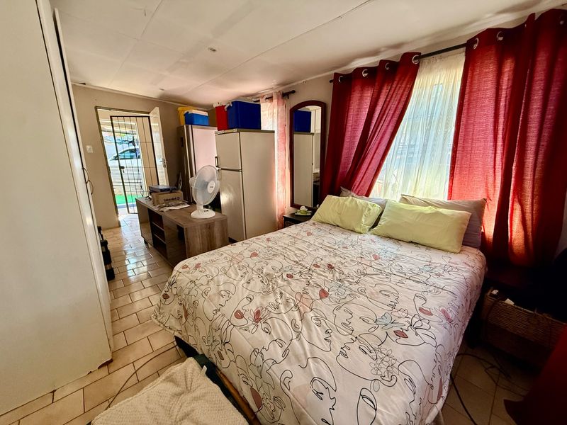 A bedroom featuring tiled flooring, a built-in cupboard, and direct access to an exterior security gate.