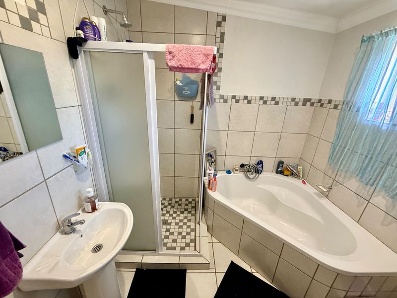 A functional bathroom featuring a corner bathtub, a separate shower enclosure, and a pedestal basin with tiled wall finishes.