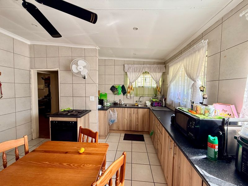 Functional kitchen featuring wood-look cabinetry, dark laminate countertops, tiled walls, and integrated cooking appliances, offering a practical layout for daily use.