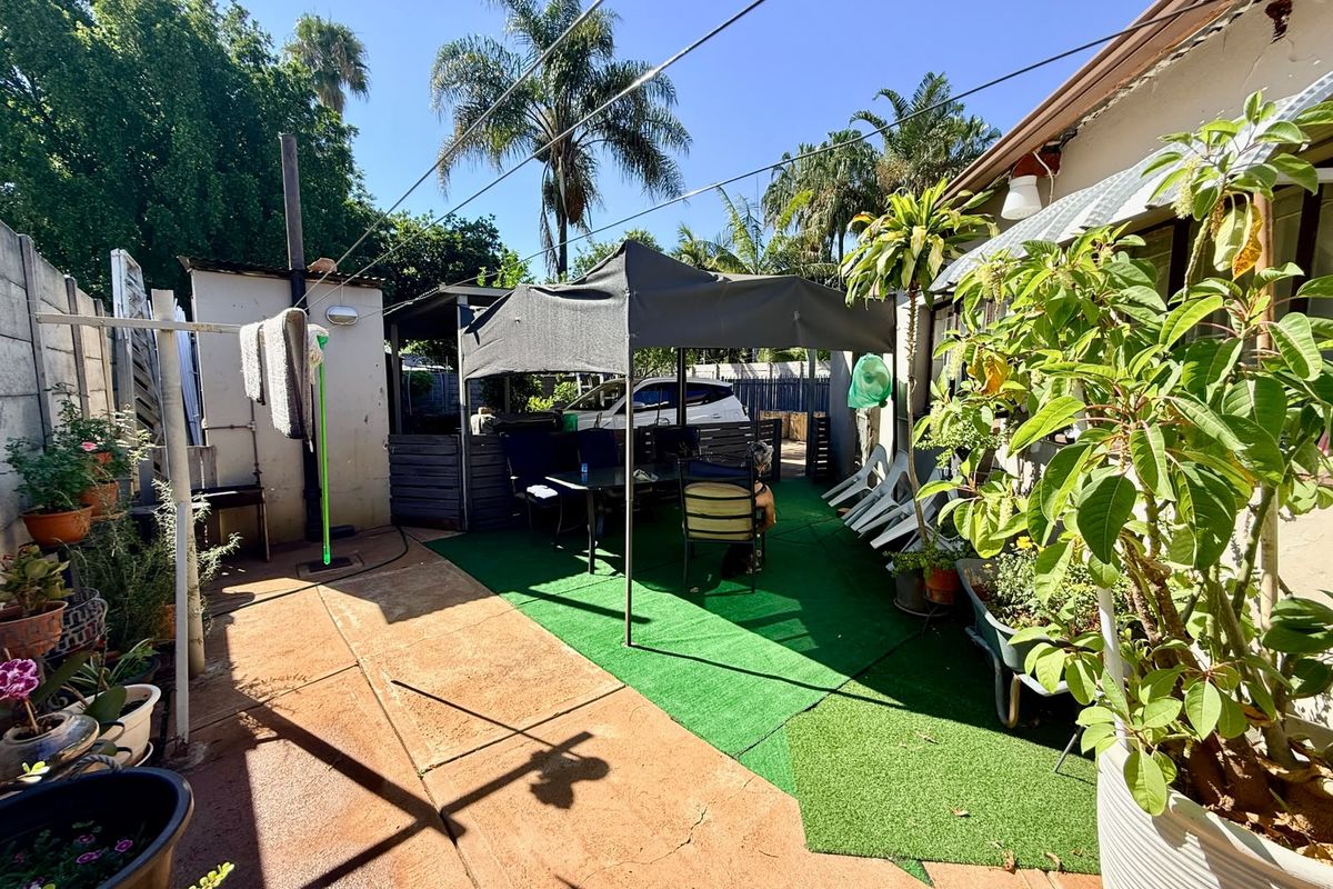 A rear outdoor area featuring concrete paving, artificial grass, and a precast concrete boundary wall, providing a functional space for outdoor activities.