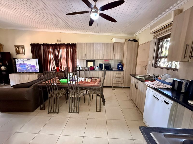 Open-plan living and kitchen area featuring tiled flooring, timber-look cabinetry, and a ceiling fan, creating a functional combined space.