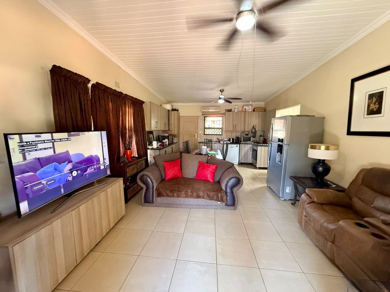 Spacious open-plan living and kitchen area featuring tiled floors, tongue and groove ceilings, and functional built-in cabinetry.