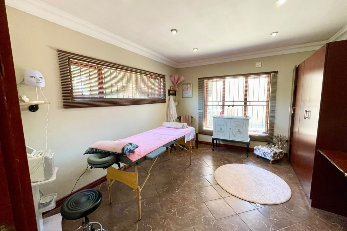 A functional bedroom space featuring tiled flooring, recessed downlighting, built-in cabinetry, and windows fitted with venetian blinds and security bars.