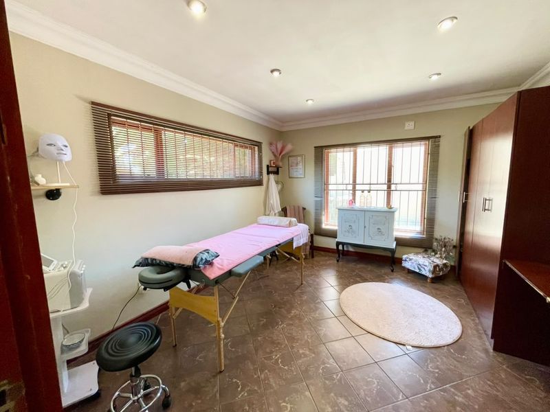 A functional bedroom space featuring tiled flooring, recessed downlighting, built-in cabinetry, and windows fitted with venetian blinds and security bars.