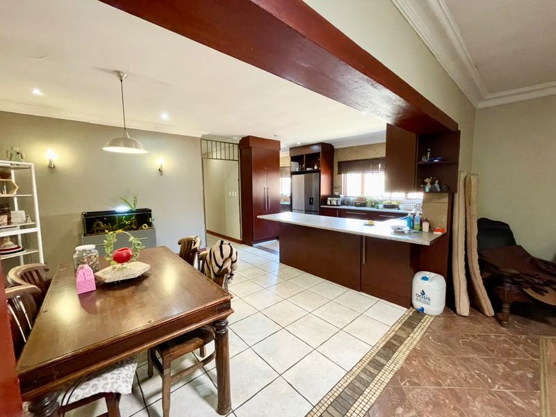 Open plan kitchen and dining area featuring dark wood cabinetry, a central kitchen island, tiled flooring, and recessed lighting.
