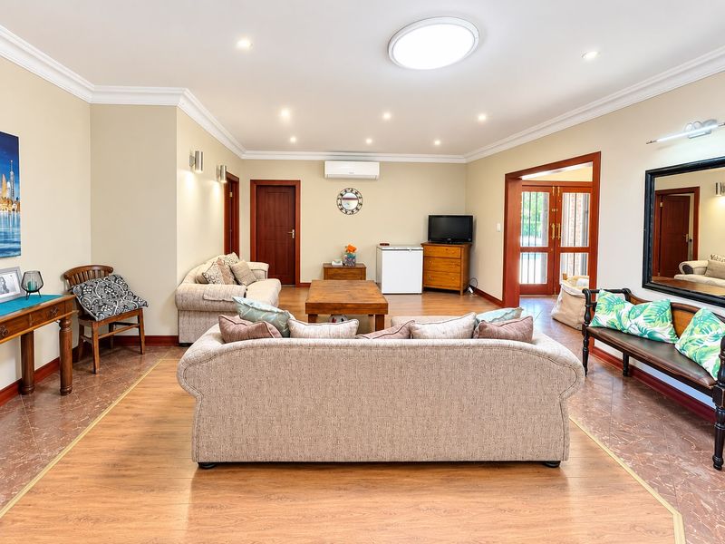 Spacious living room featuring laminate flooring with tiled borders, recessed downlighting, split system air conditioning, and direct access to the outdoor area.