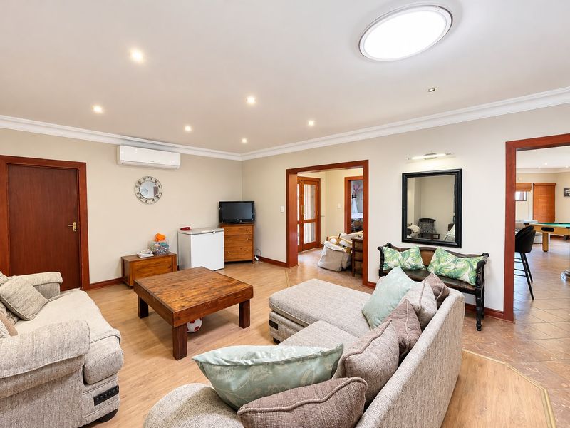 Spacious living room featuring laminate flooring, recessed downlighting, and a split system air conditioner, with open access to adjacent living areas.