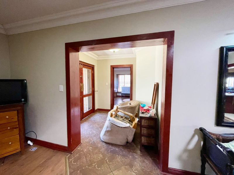 A transitional hallway space featuring tiled flooring and prominent timber door frames connecting the living area to the entrance and adjacent rooms.
