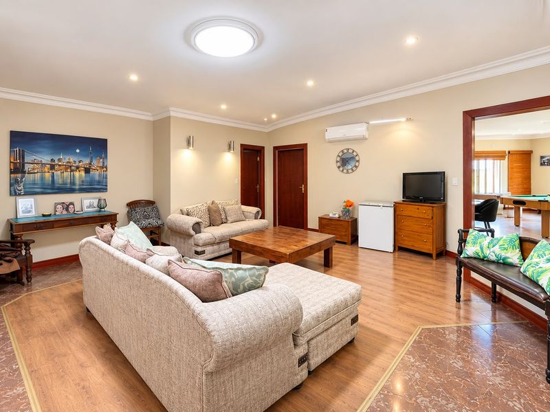 Spacious living room featuring laminate flooring, recessed lighting, and a wall-mounted air conditioning unit, providing a comfortable and functional living space.