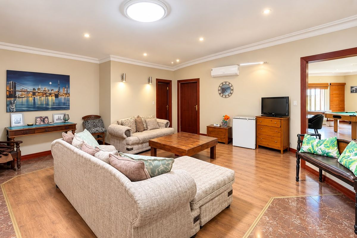 Spacious living room featuring laminate flooring, recessed lighting, and a wall-mounted air conditioning unit, providing a comfortable and functional living space.