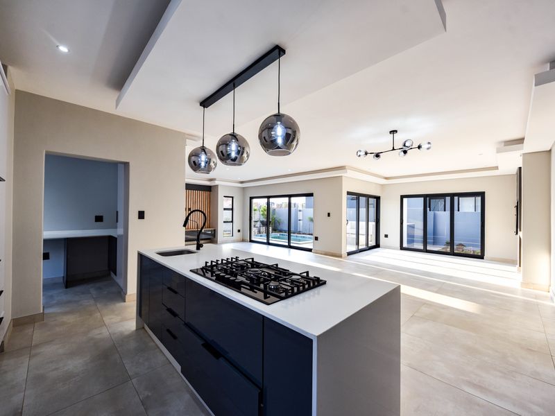 Spacious open-plan living area featuring a modern kitchen island with gas hob, sleek cabinetry, and large sliding doors opening to the outdoor area.