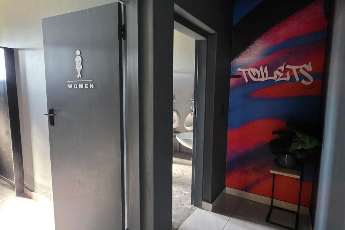 A functional commercial-style bathroom facility featuring designated women's access and a separate area with urinals and wash basins.