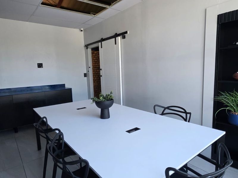 A functional office space featuring a sliding barn door, built-in shelving, and tiled flooring, currently used as a meeting room.
