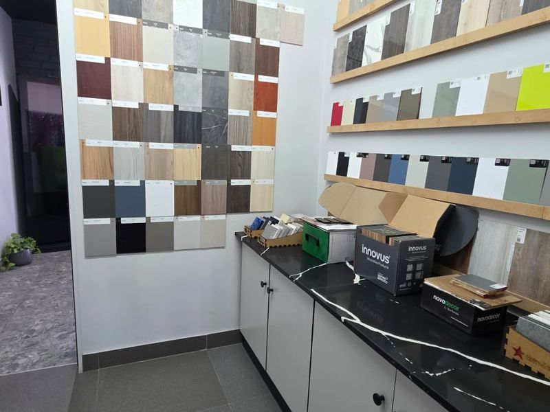 A commercial showroom or design studio space featuring built-in cabinetry with stone countertops and extensive wall-mounted material sample displays.