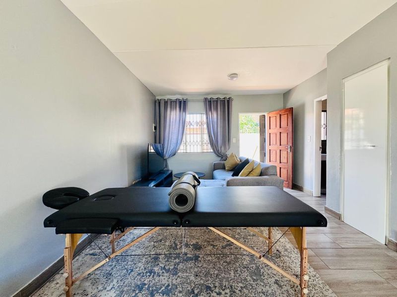 A functional living area featuring tiled flooring and direct access to the exterior, providing a versatile space for relaxation or home activities.